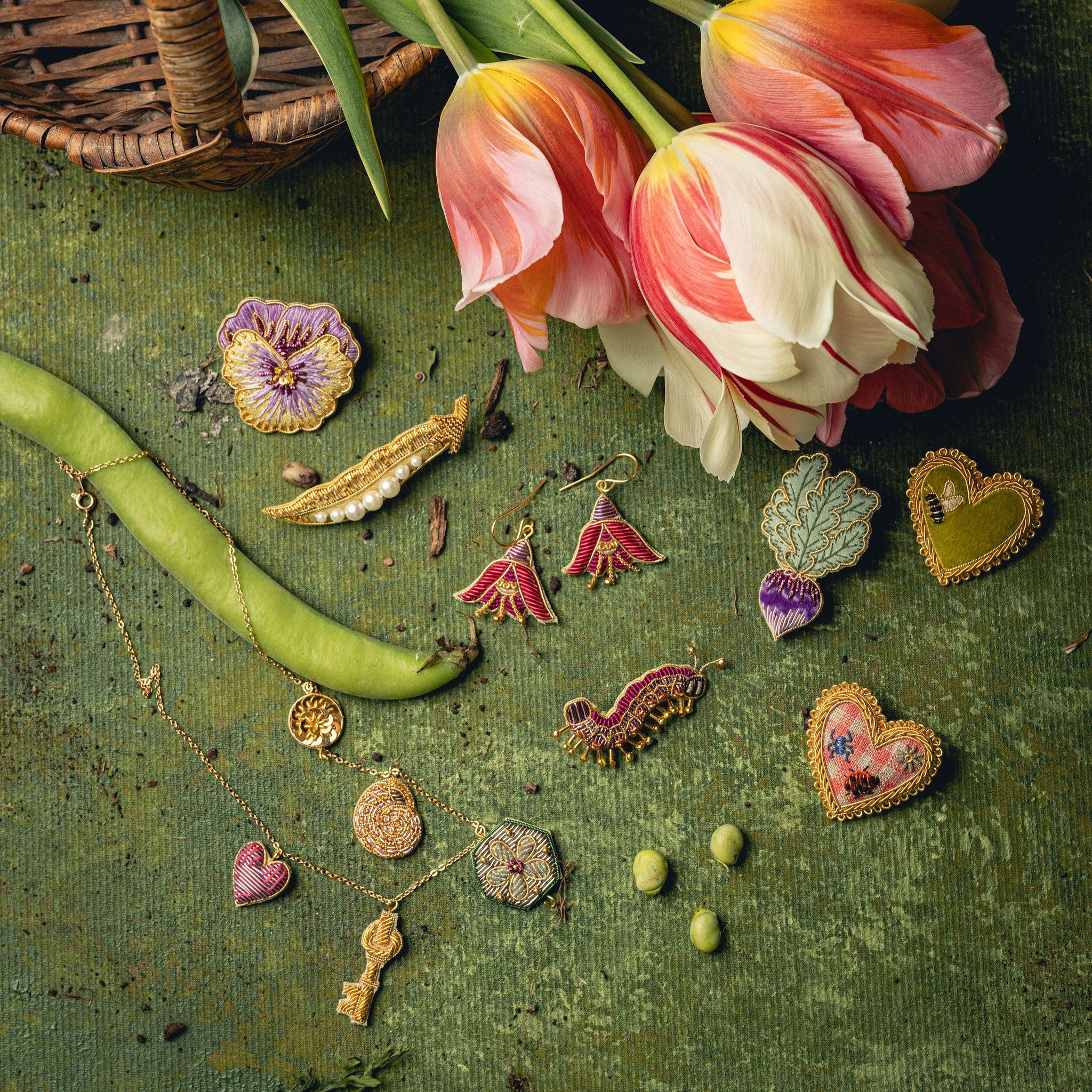 How Does Your Garden Grow? Collection of Hand Embroidered Jewellery - Selection of embroidered jewellery on a green background, with tulips and runner beans