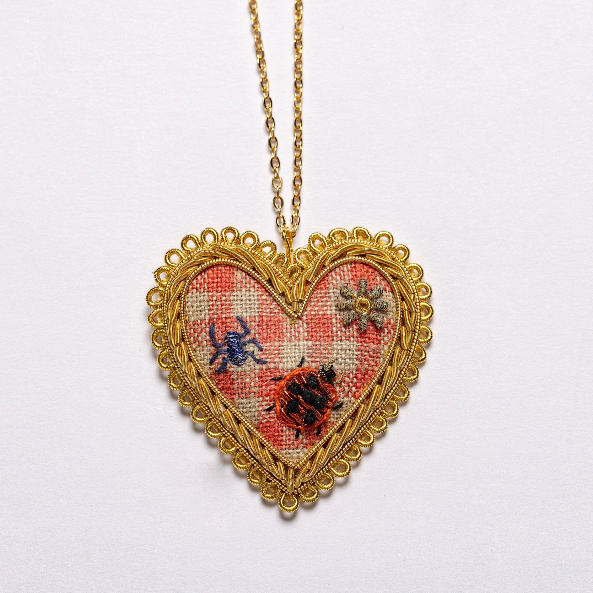 Picnic Heart Necklace - Hand Embroidered necklace detail photo showing gingham background, embroidered daisy and bugs