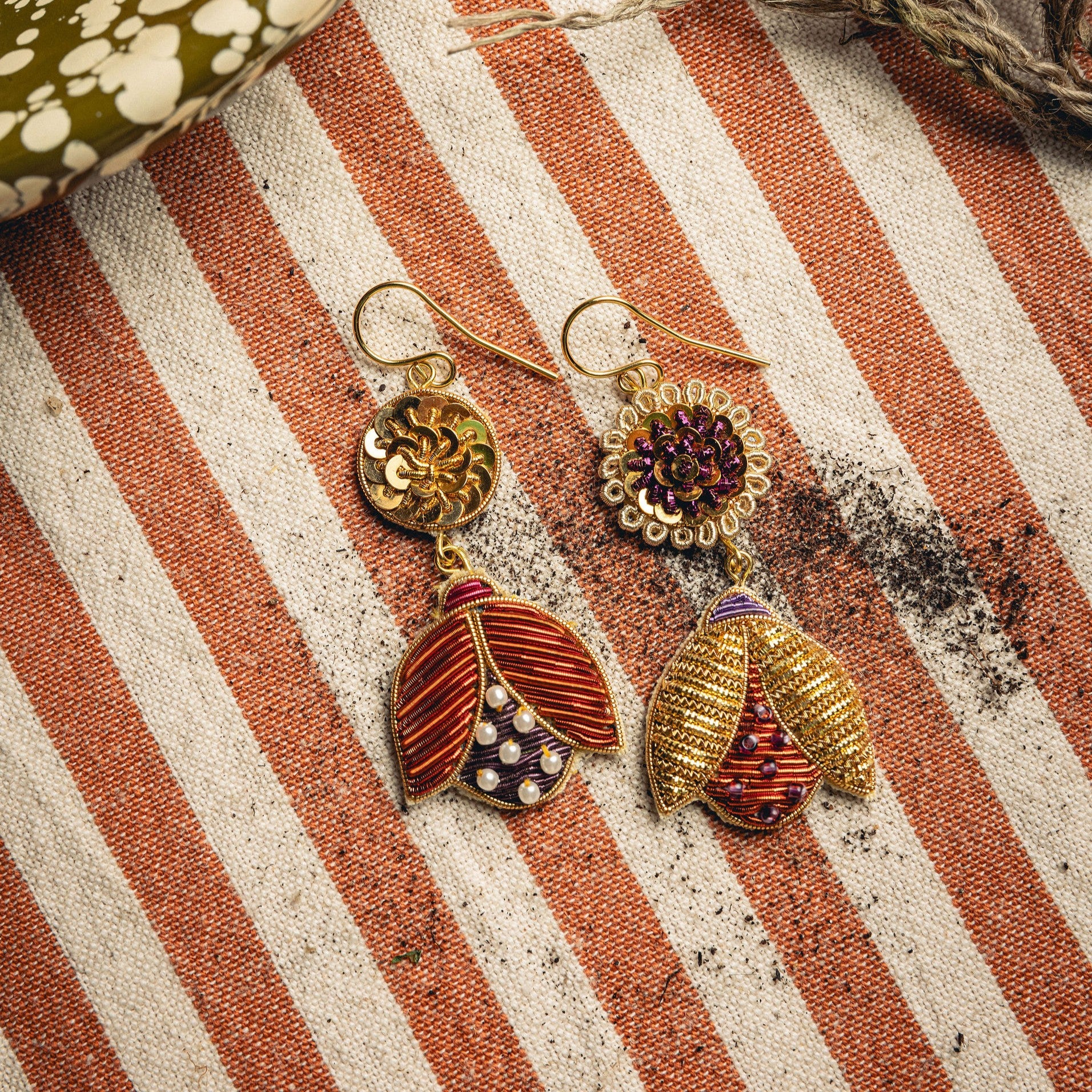 Beetle Earrings - Hand Embroidered beetle earrings on a striped background with soil