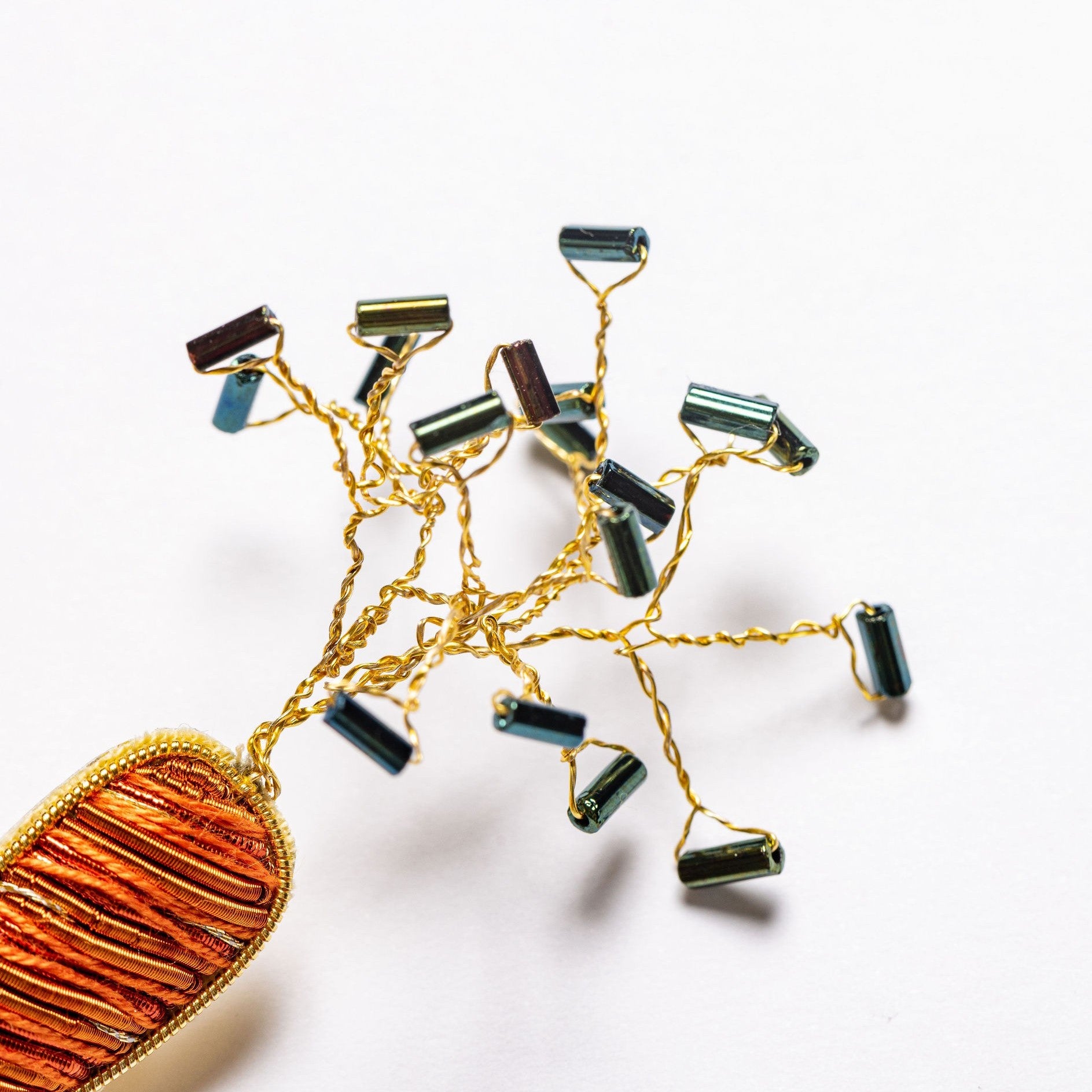 Carrot Brooch - Hand Embroidered carrot brooch close up of wire and bead leaves on a white background