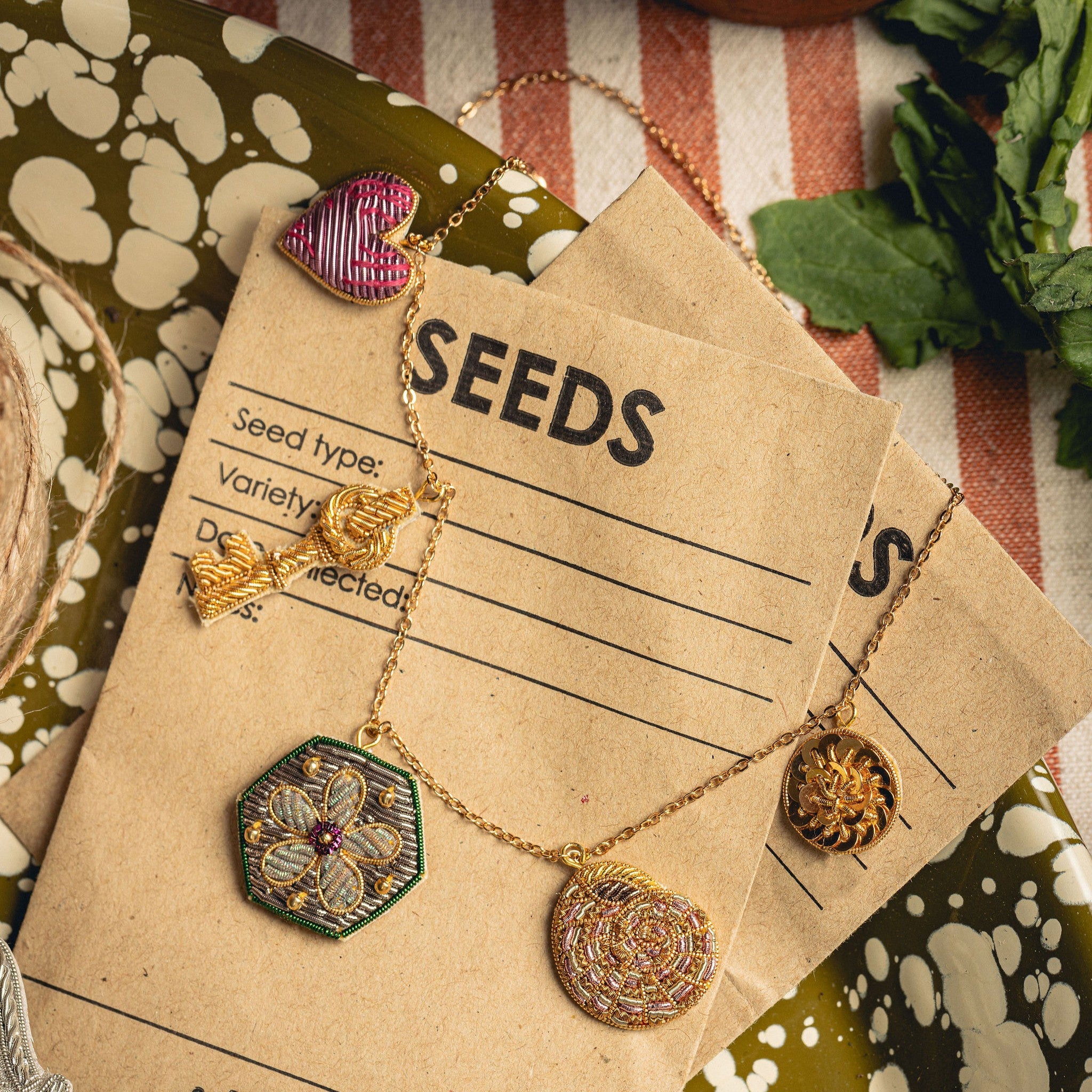 Garden Charm Necklace - Hand Embroidered charm necklace photographed on seed packets