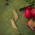Golden Pea Earrings - Hand Embroidered earrings shown on a green background with radishes and leaves