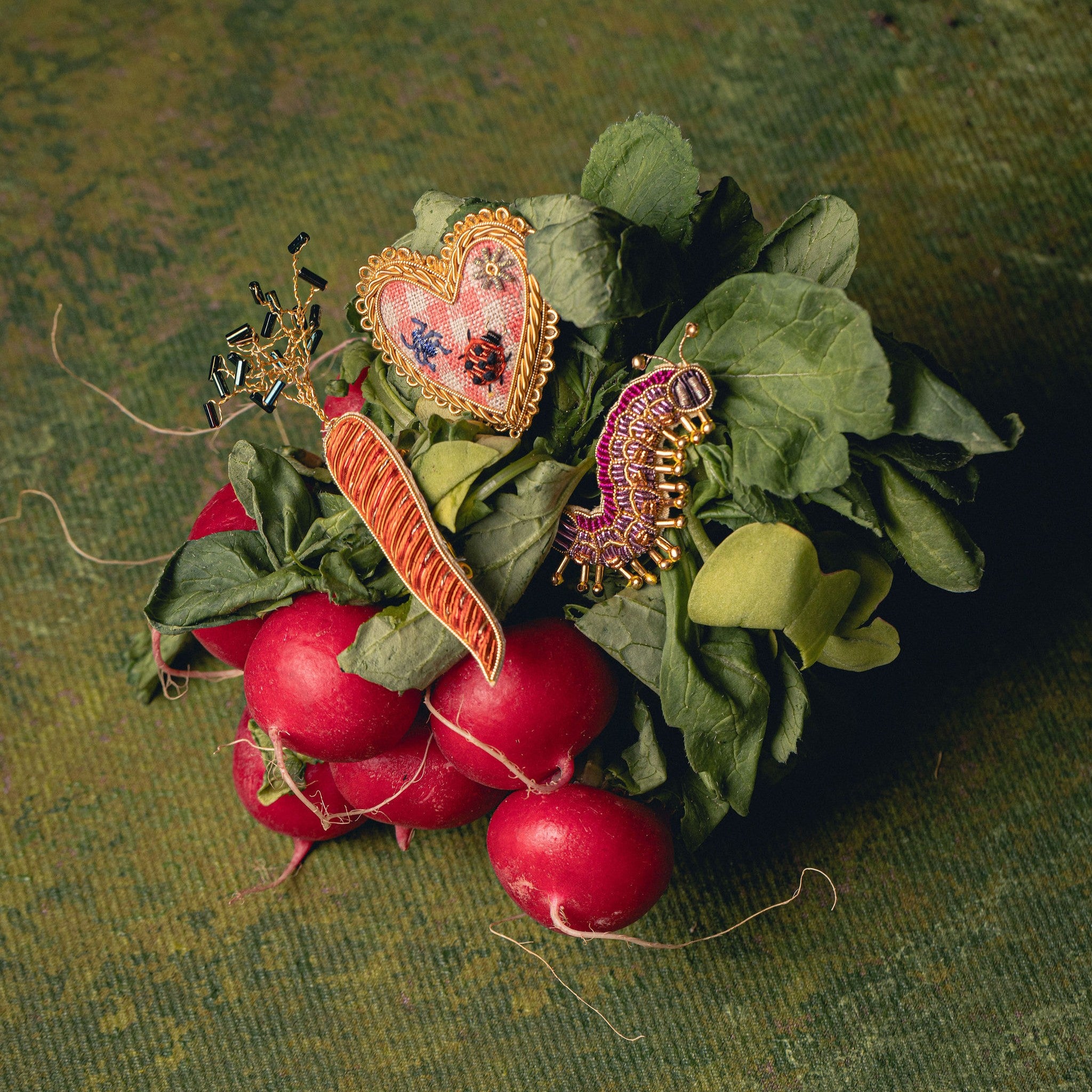 How Does Your Garden Grow? Collection of Hand Embroidered Jewellery - Shown on radishes with green leaves against a green background