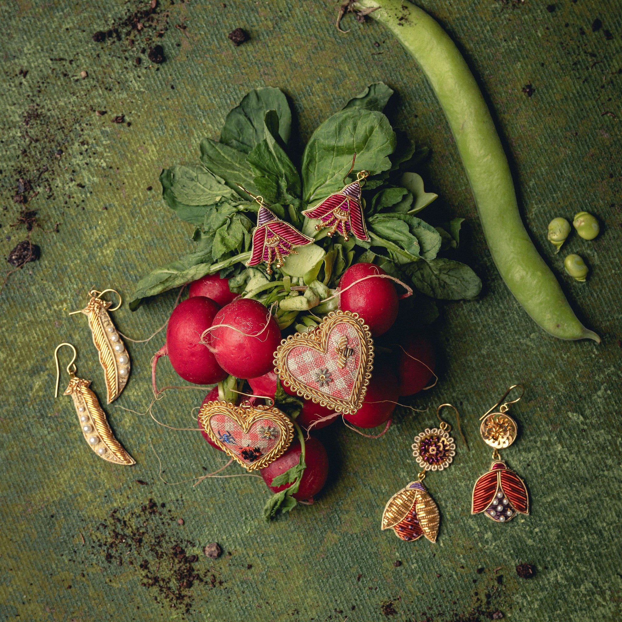 How Does Your Garden Grow? Collection of Hand Embroidered Jewellery - Collection of embroidered earrings displayed on a green background with radishes and runner beans 