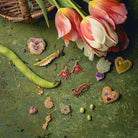 How Does Your Garden Grow? Collection of Hand Embroidered Jewellery - Selection of embroidered jewellery on a green background, with tulips and runner beans
