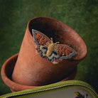 Kaleidoscope Butterfly Brooch - Hand Embroidered butterfly brooch on a terracotta pot with a green background