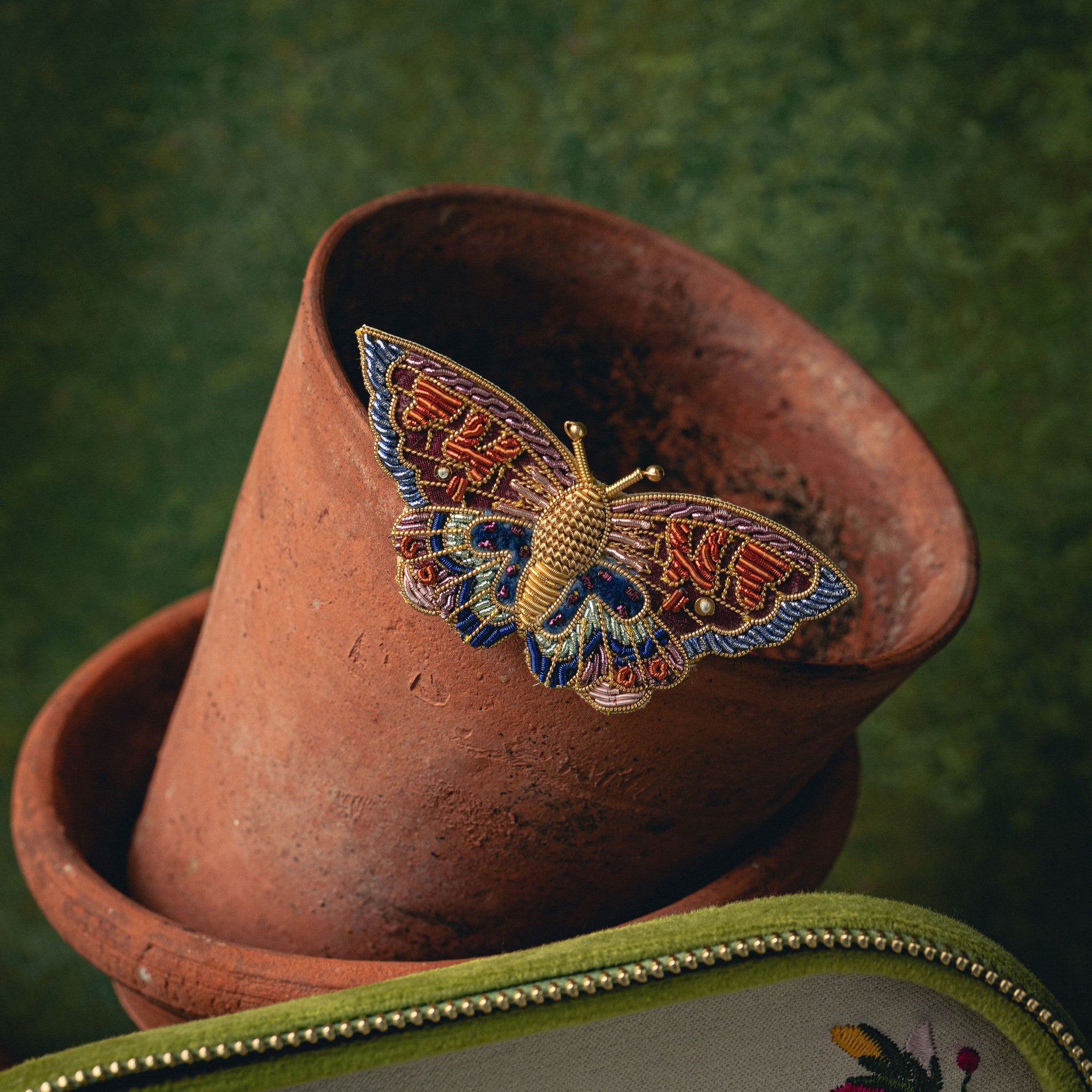 Kaleidoscope Butterfly Brooch - Hand Embroidered butterfly brooch on a terracotta pot with a green background