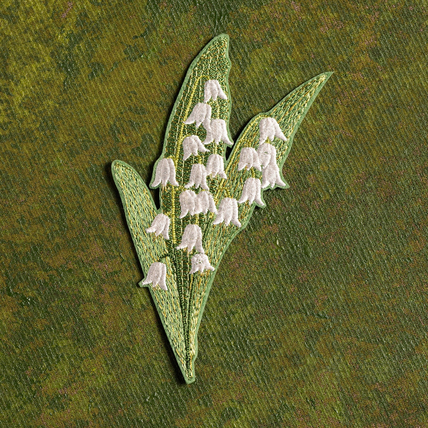 Lily of the Valley Flower Embroidered Patch - Embroidered patch of white flowers with green leaves on a green background