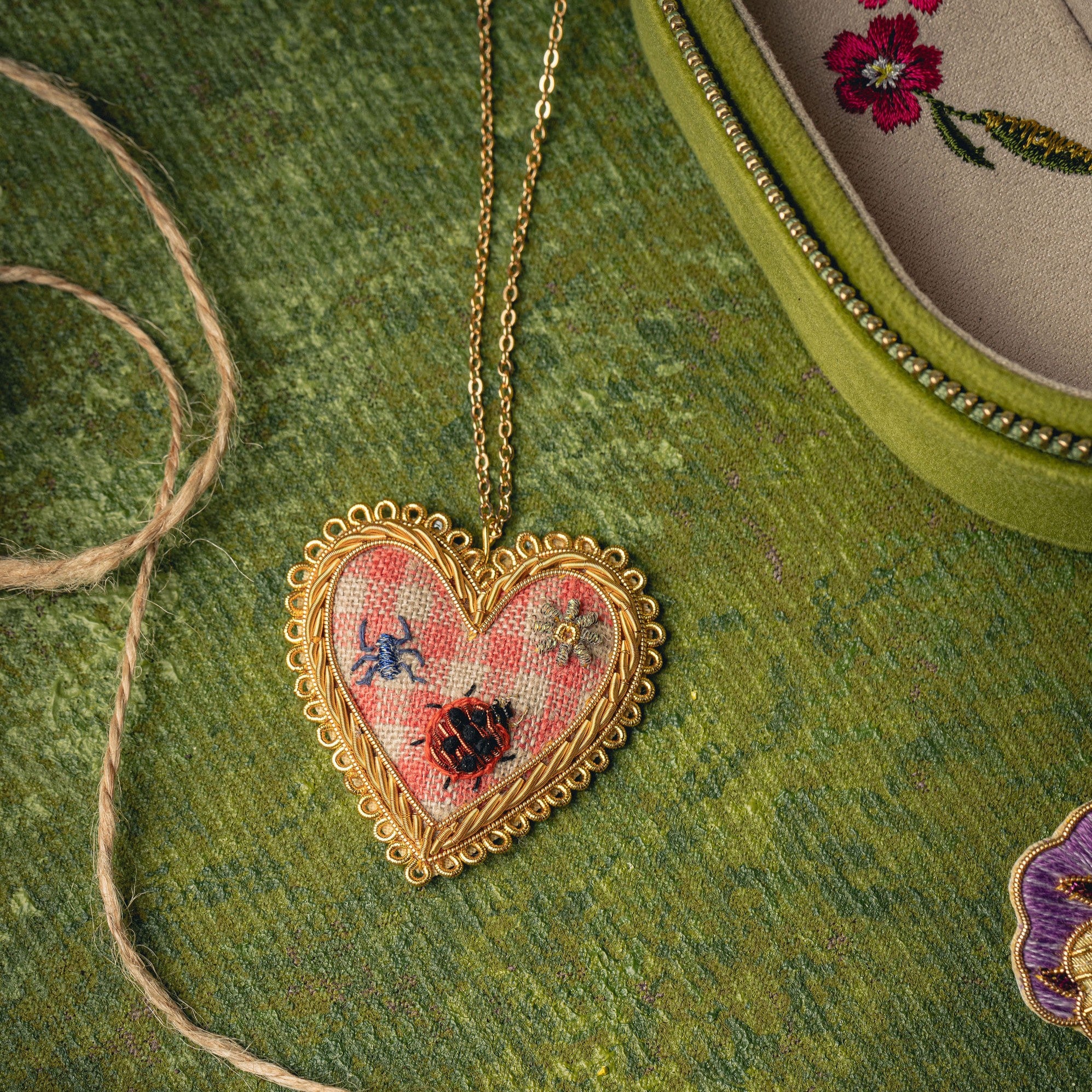Picnic Heart Necklace - Hand Embroidered necklace shown on a green background 