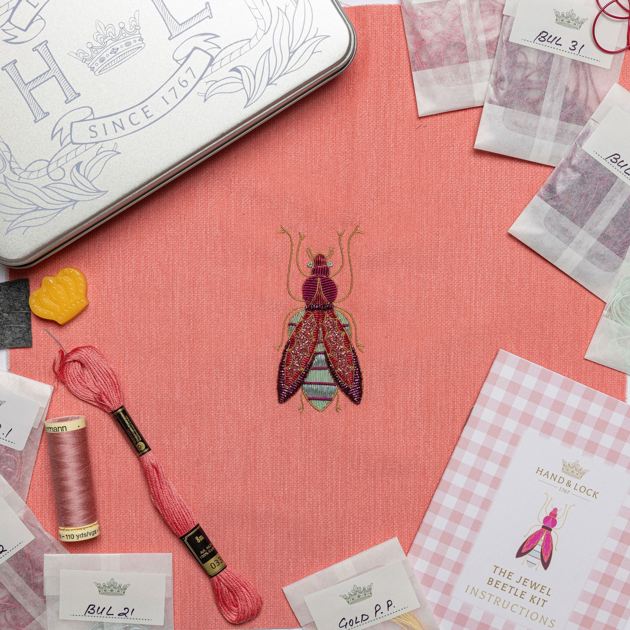 The Jewel Beetle Kit - Embroidery kit with a completed beetle design on a pink fabric base