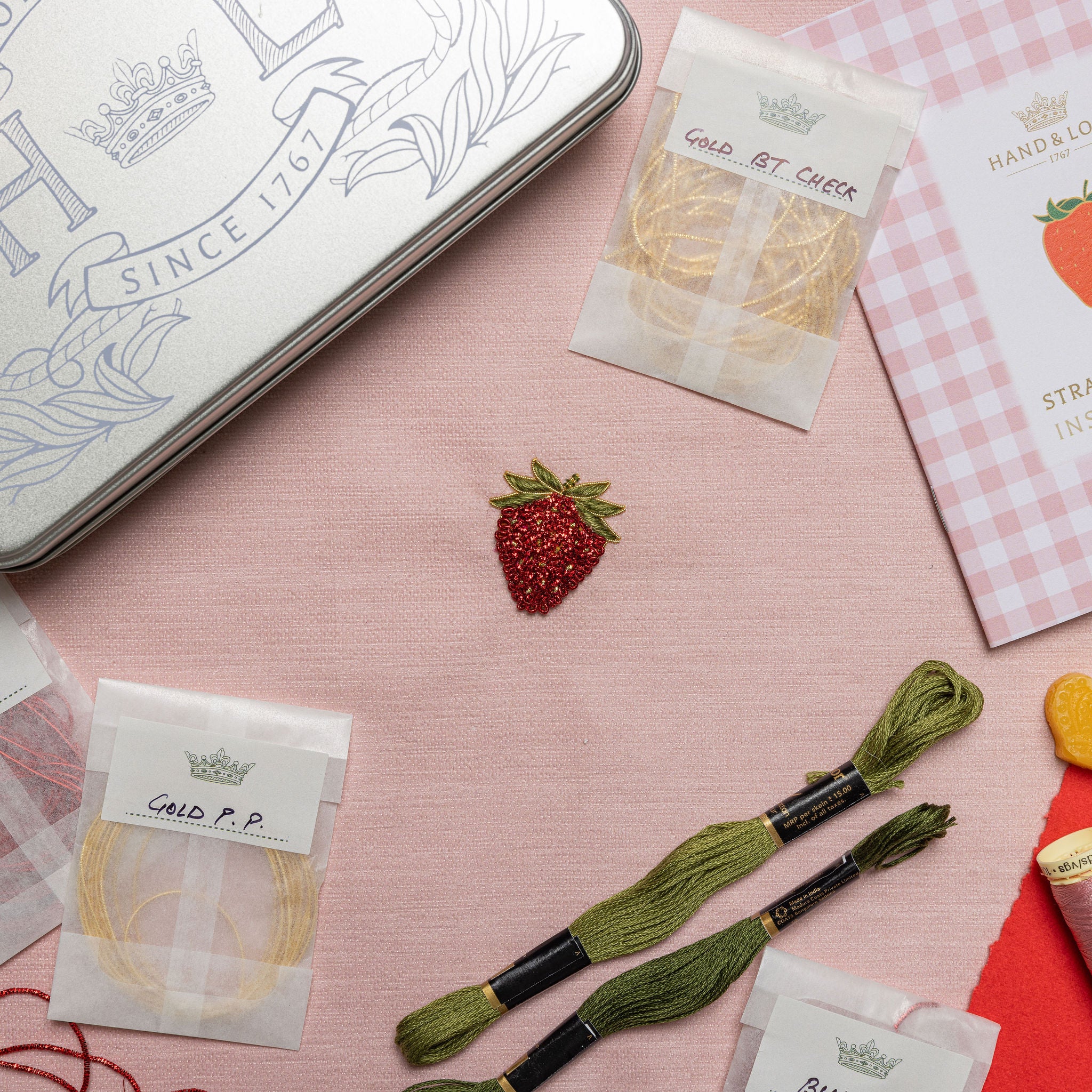 The Strawberry Kit - Embroidery kit with strawberry design on a pink surface