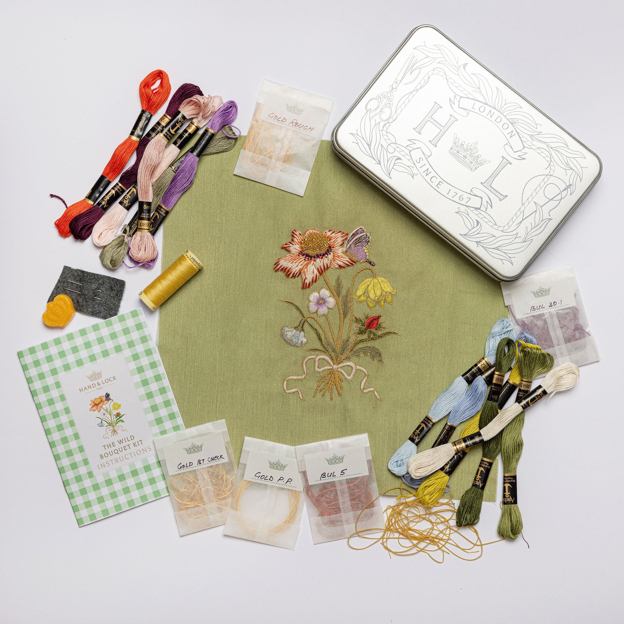The Wild Bouquet Kit - Floral embroidery kit with materials and a completed floral design on fabric.