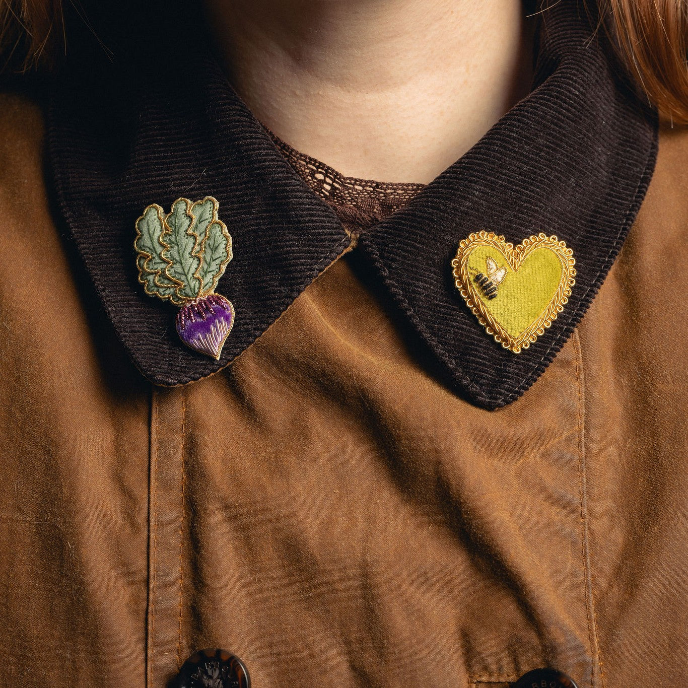 The Garden Embroidered Brooches - Radish and Bee Heart Brooches displayed on jacket collar